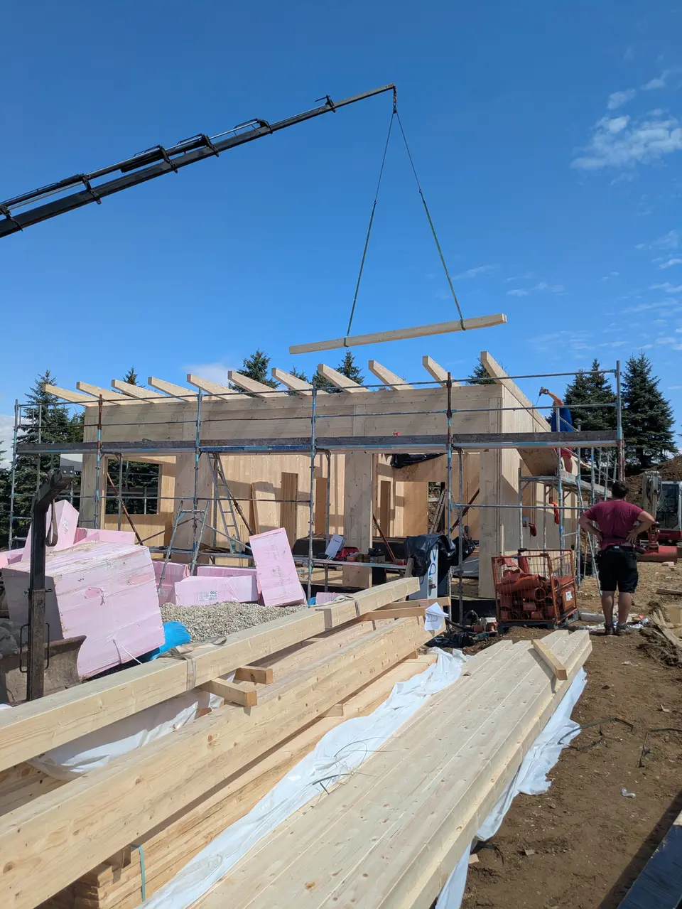 Kran hebt ein Holzelement auf das Gebäude